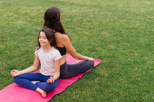 Foto gratuita hija y madre meditando en la hierba verde