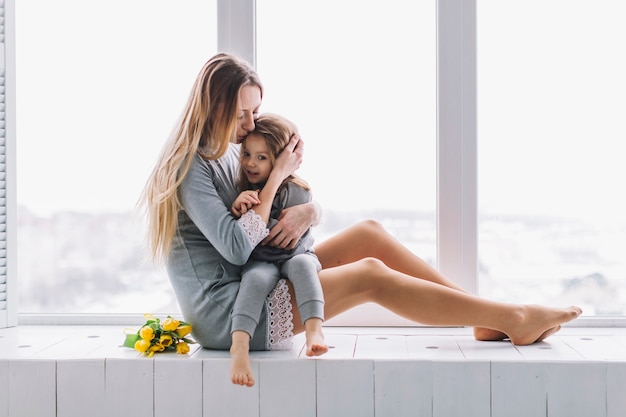 Foto gratuita hija y madre sentadas enfrente de ventana