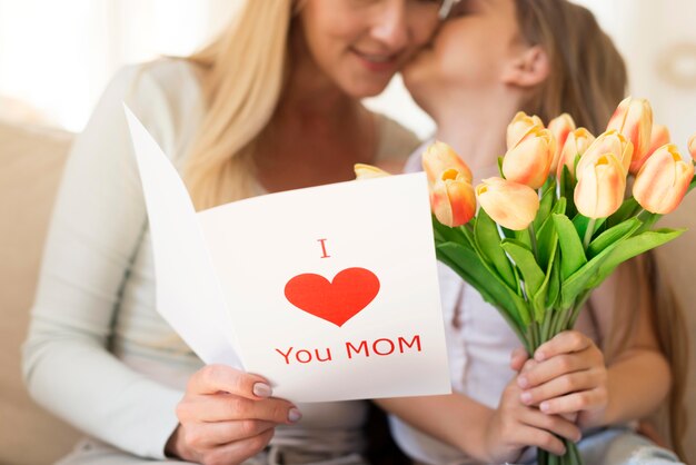 Hija madre sorprendente con ramo de flores y tarjeta