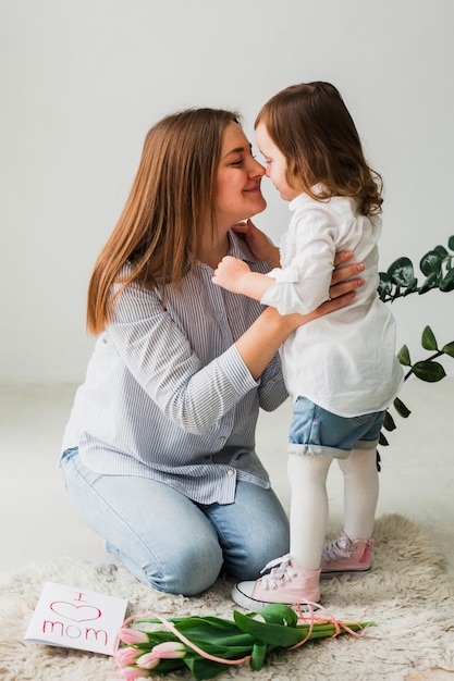 Foto gratuita hija y madre tocando narices cerca de tarjeta de felicitación