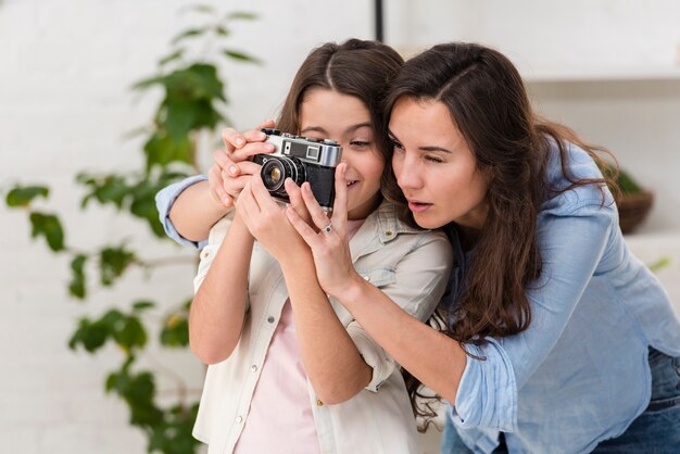 Hija y madre tomando una foto con una cámara juntas