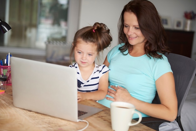 Hija y madre usan tecnología por computadora.