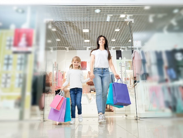 Hija manteniendo la mano de la madre y saliendo de la tienda