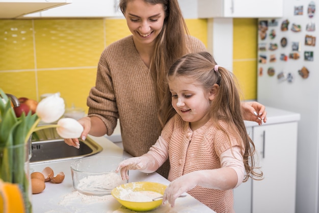 Hija mezclando harina con huevos en un tazón