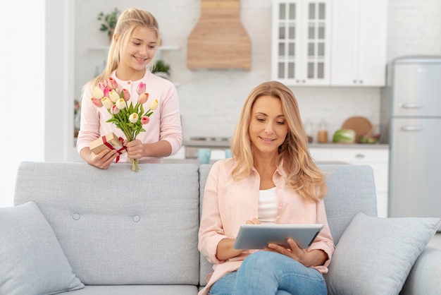 Hija ofreciendo flores a su madre.