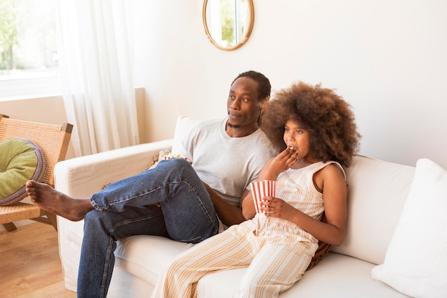 Hija y padre relajándose en casa viendo películas