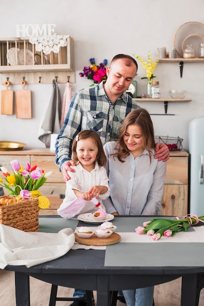 Hija con padres haciendo cupcake en la cocina