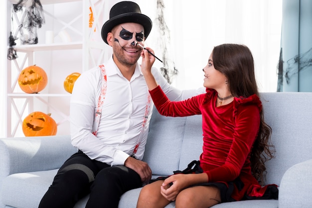 Foto gratuita hija pintando papás cara para halloween