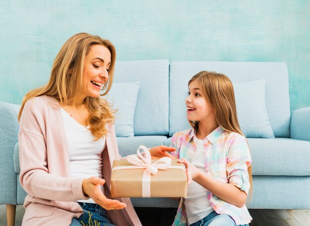 Hija presentando caja de regalo para madre.