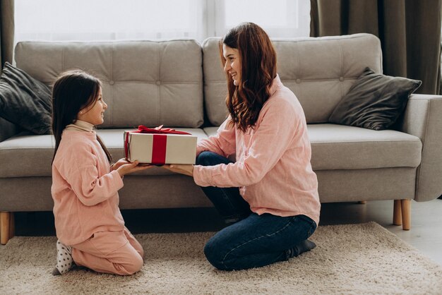 Hija presentando caja de regalo a su madre en el día de la madre.