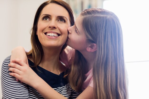 Hija que besa a su madre en la sala de estar