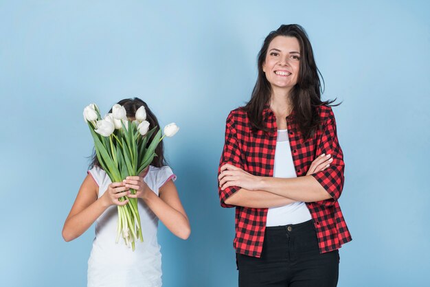 Hija que cubre la cara con tulipanes cerca de madre