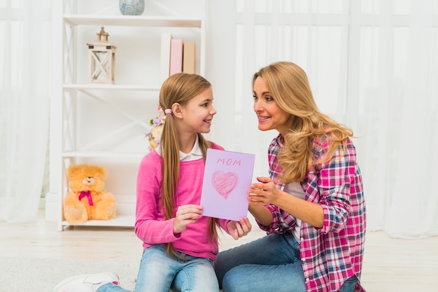 Hija que da la tarjeta de felicitación a la madre.