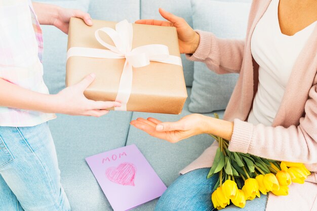 Hija que presenta una caja de regalo para mamá en la celebración del día de la madre