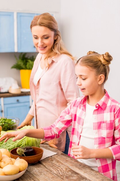Hija sonriente ayudando a su madre en la cocina