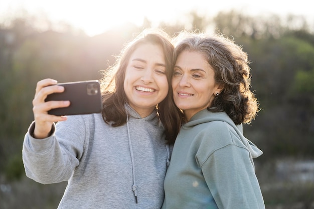 Hija sonriente tomando un selfie con su madre al aire libre