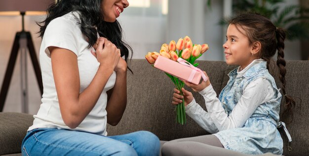 Hija sorprende a mamá con flores y regalos