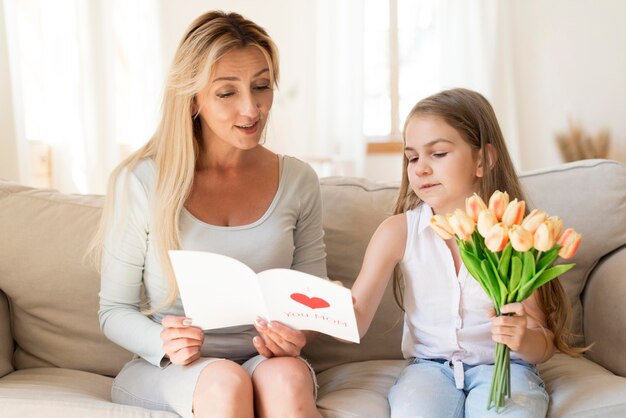 Hija sorprendente madre con flores y tarjeta.