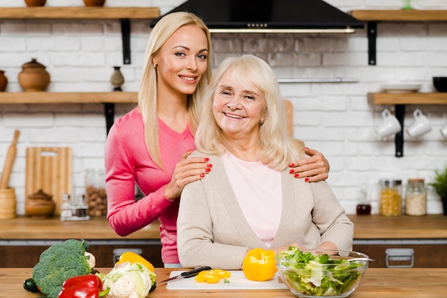 Hija sosteniendo a su madre y sonriendo