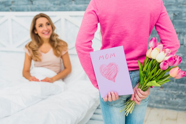 Hija con tarjeta de felicitación y tulipanes para la madre