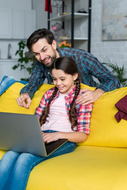 Hija usando la computadora portátil en la sala de estar