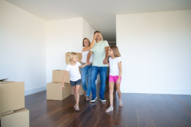 Hijas alegres y su mamá líder papá con los ojos cerrados en su nuevo apartamento