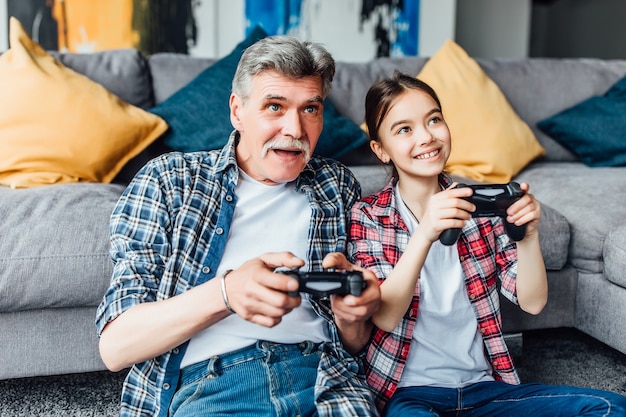 Foto gratuita ¡hijita muy sonriente jugando a la consola con el abuelo!