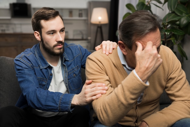 Foto gratuita hijo adulto reconfortante padre molesto