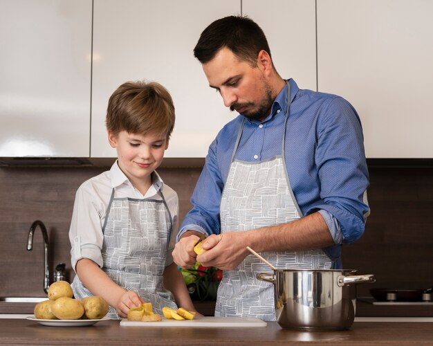 Hijo de ángulo bajo ayudando al padre mientras cocina