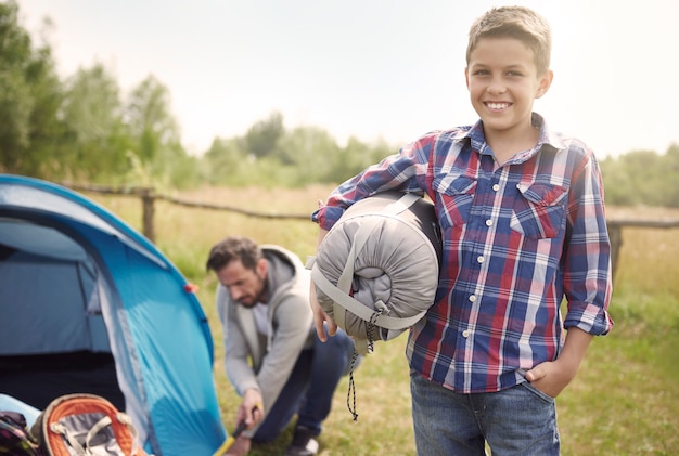 Hijo ayudando a su padre en el camping.