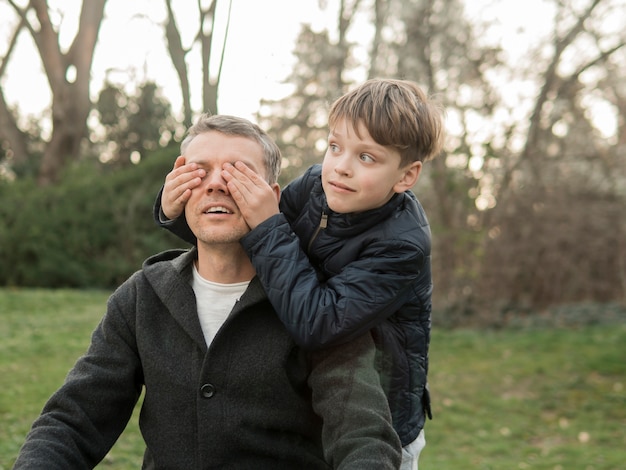 Hijo cubre los ojos de su padre en el parque