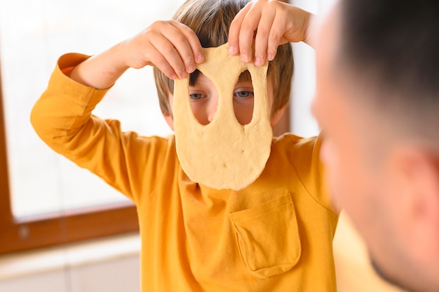 Foto gratuita hijo con una divertida máscara de masa