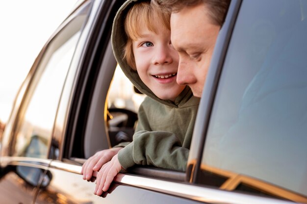 Hijo feliz en el coche con el padre en un viaje por carretera