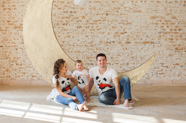 Hijo feliz del padre, de la madre y del niño de la familia cerca de una pared de ladrillo en blanco en el cuarto.