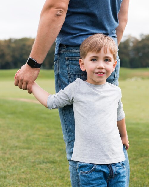 Hijo feliz sosteniendo la vista frontal de la mano de su padre