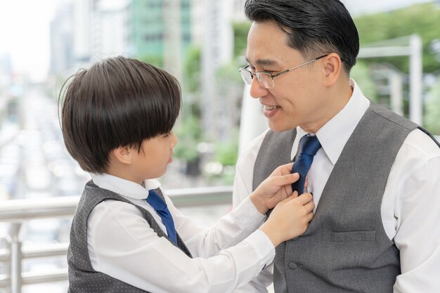 Hijo hizo el cuello del traje para su padre en el distrito de negocios urbano.