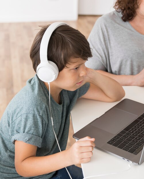 Hijo mirando en la computadora portátil junto a mamá