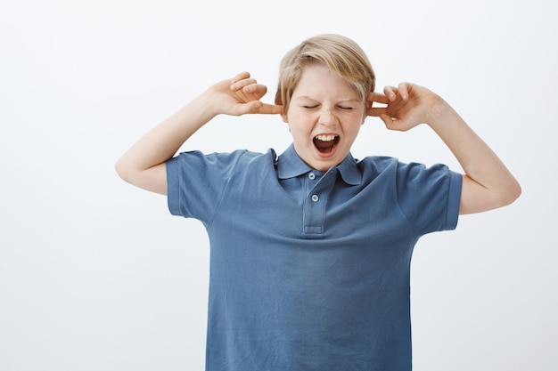 Foto gratuita hijo no quiere ser obediente, hacer ruido y portarse mal. retrato de niño infeliz disgustado de pie