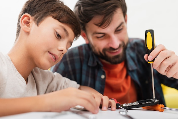 Foto gratuita hijo y padre arreglando un teléfono