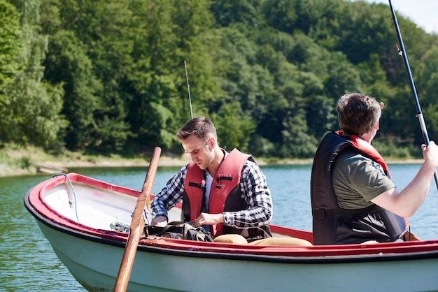 Hijo y padre en barco hacen preparativos para pescar