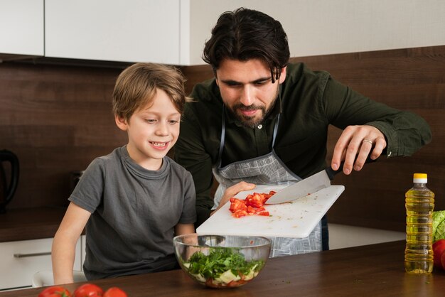 Hijo y padre cocinando ensalada en casa