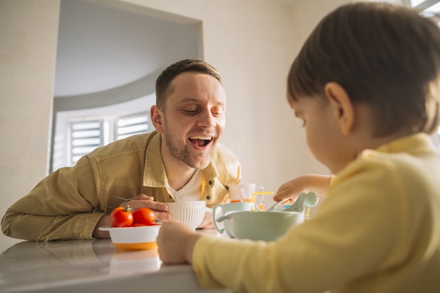 Foto gratuita hijo y padre comiendo en la cocina