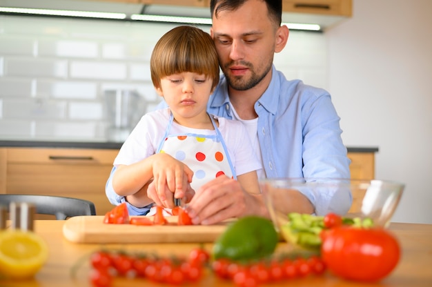 Hijo y papá cortando tomates vista frontal