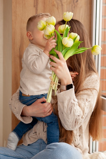 Foto gratuita hijo regalando flores a mamá