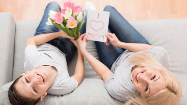 Hijo sorprendente madre con flores y tarjeta