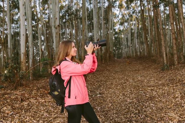 Hiker femenino que toma la imagen de los árboles forestales