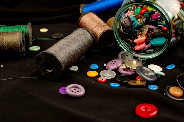 Hilos y botones colorida composición vintage de plástico sobre un tejido marrón