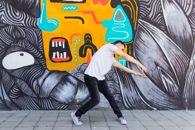 Hip hopper realizando danza delante de la pared de graffiti