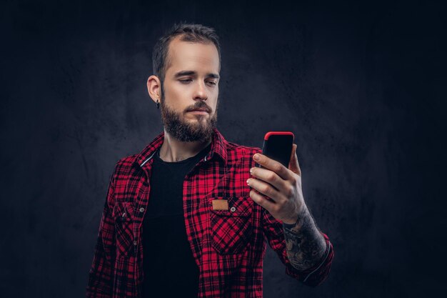 Un hipster barbudo leyendo mensajes de texto en su smartphone.