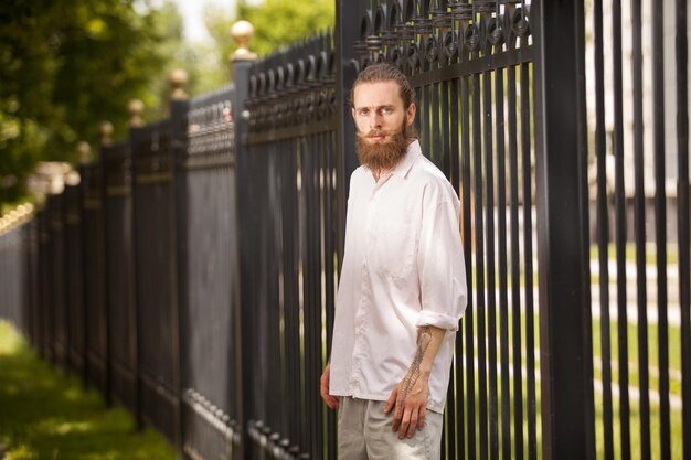 Hipster barbudo de moda posando junto a una valla. Estilo y diversidad